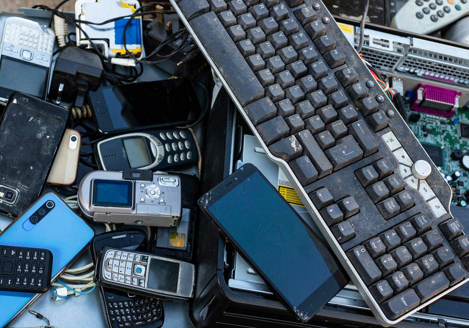 Close up on pile of mixed electronic waste, old-broken computer parts and cell phones